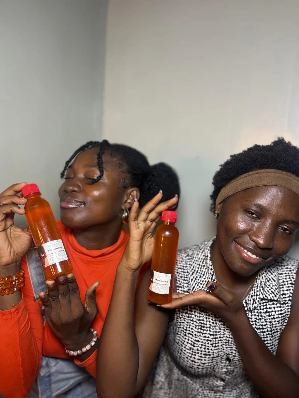 Deux amies souriantes présentant chacune un flacon de shampooing